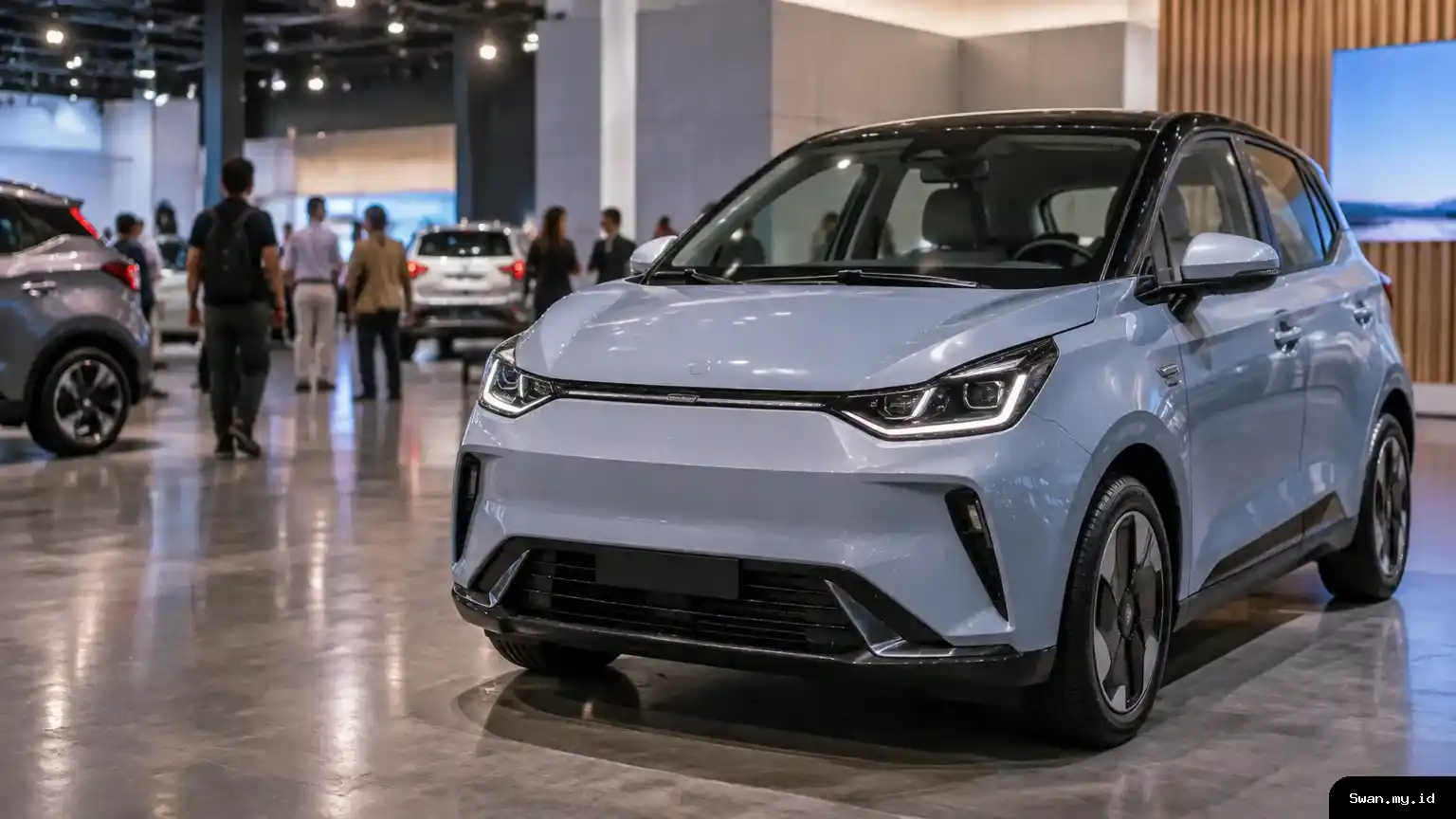 A compact electric hatchback sits under exhibition lighting as visitors look around the display, illustrating interest in updated small electric cars. Compact electric hatchback at an indoor automotive exhibition
