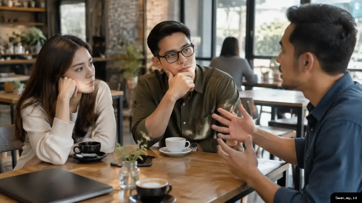 Three adults at a cafe table as one person speaks and another waits to respond.