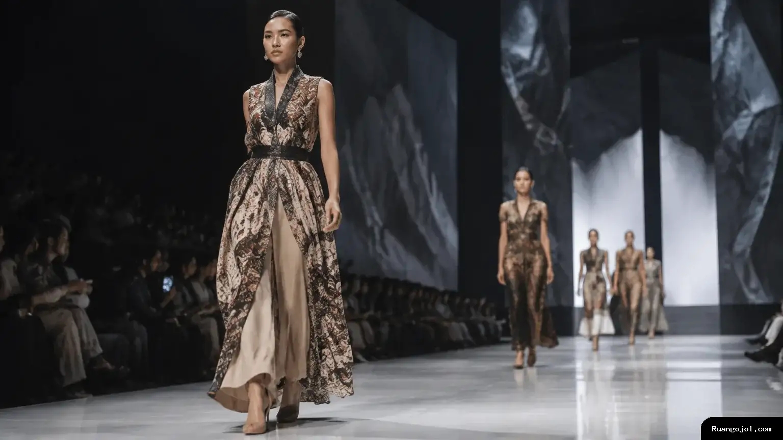 Suasana peragaan busana dengan model berjalan di runway mengenakan rancangan bernuansa wastra Indonesia. Penonton terlihat di sisi panggung, menggambarkan ruang promosi bagi karya fesyen lokal. Model memperagakan busana bernuansa wastra di runway dengan penonton di sisi panggung.